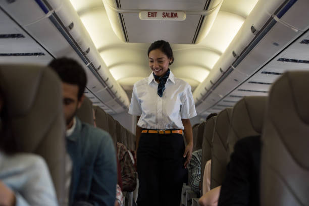 istock Friendly flight attendant walking the aisle in an airplane 1028463146