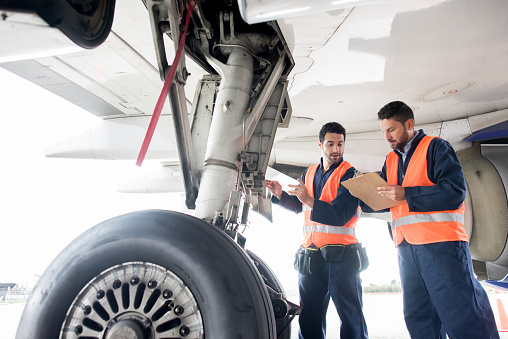 Ground crew working at the airport fixing airplanes and checking the landing gear