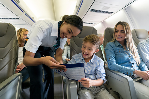 Portrait of a friendly air hostess helping a boy in an airplane and looking very happy - travel concepts.