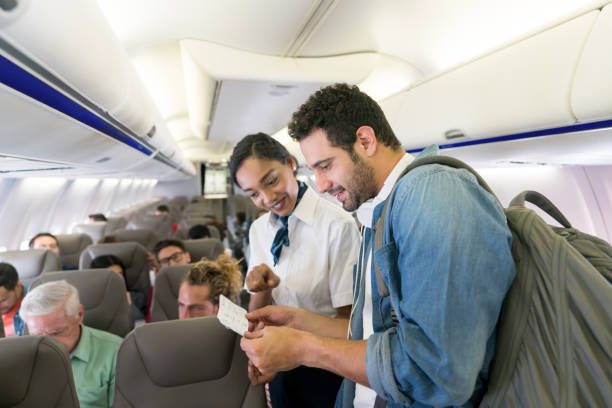 istock Flight attendant helping man find his seat in an airplane 1028463220