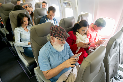 Group of passengers traveling by air and using cellphones on the airplane