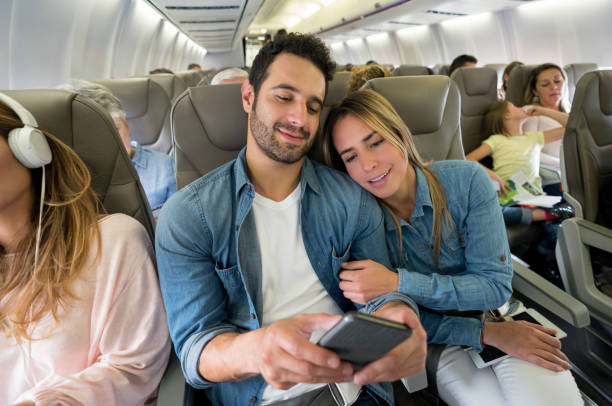 istock Couple traveling by plane and using their cell phone onboard 1028463264