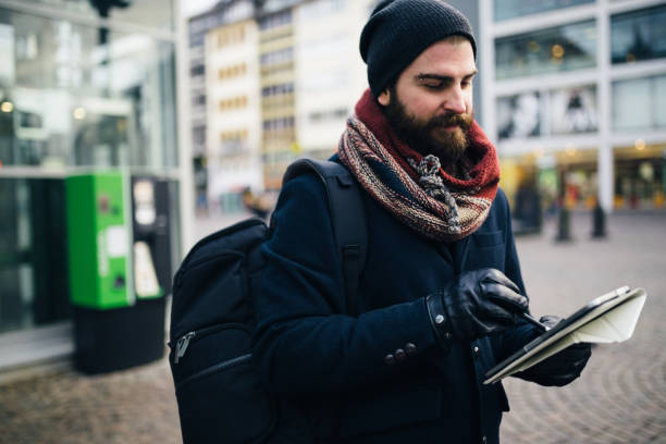 istock Man with a backpack walking in the city street and using digital tablet 1028465488