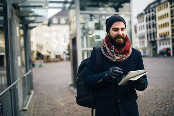 istock Man with a backpack walking in the city street and using digital tablet 1028465638