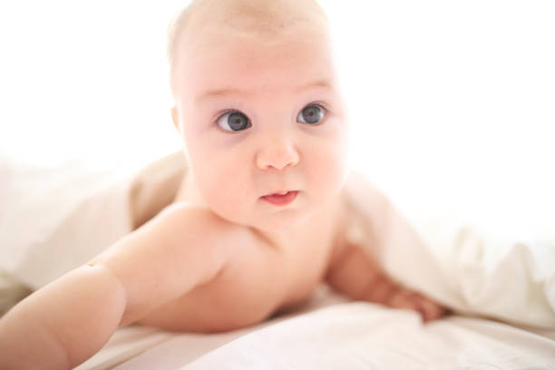 istock Cute baby on white bed 1028465874