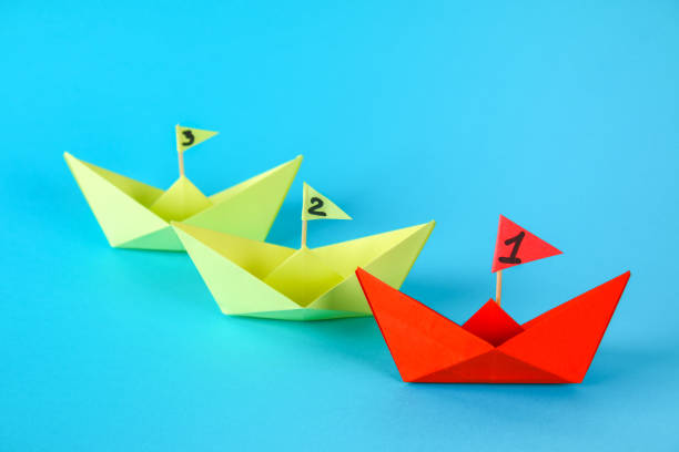 istock Three paper ships compete who swims faster. Red wins the ship. 1028468296