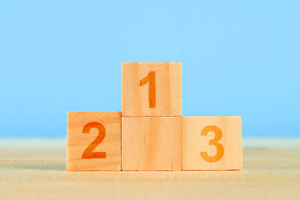 istock Achievement concept. Wooden podium standing on blue background. 1028468324