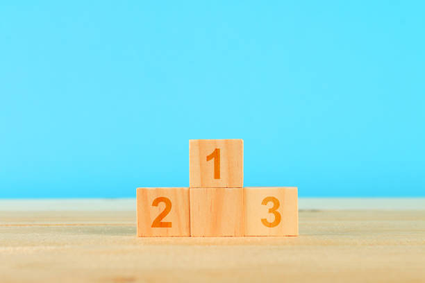 istock Achievement concept. Wooden podium standing on blue background. 1028468330