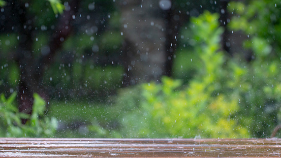 drops of rain fall on a wooden terrace and a bridge near the pool close up