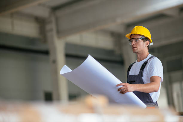 istock Handsome engineer in factory with blueprint 1028481806