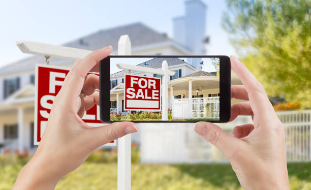 kobieta ręce gospodarstwa inteligentny telefon wyświetlanie zdjęcie na sprzedaż nieruchomości znak i dom za. - real estate house for sale sale zdjęcia i obrazy z banku zdjęć