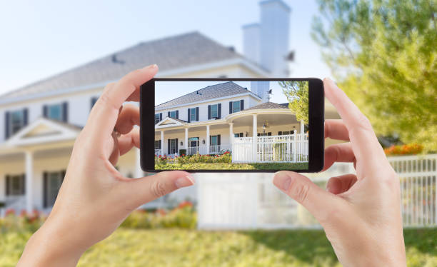 mujer manos sosteniendo elegante teléfono mostrando fotos de la casa detrás. - arquitectura fotos fotografías e imágenes de stock