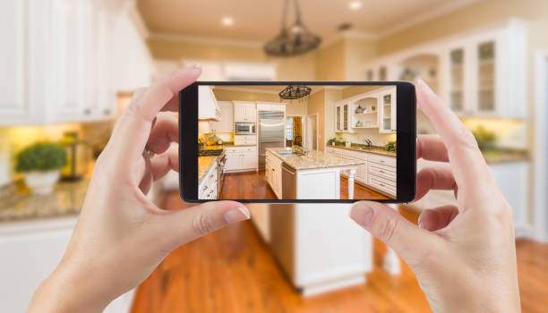vrouwelijke handen met slimme telefoon weergeven foto van keuken achter. - huis interieur fotos stockfoto's en -beelden