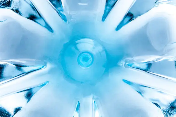 A bottom of a plastic bottle filled with fresh water - seen from above through the water.