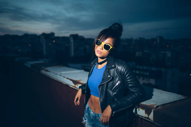 Beautiful woman with sunglasses leaning back on roof top.