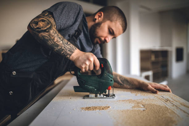 homme tatoué de handy perçage des planches et fixation nouvelle table en bois - wood saw photos et images de collection