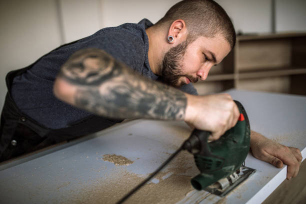 istock Tattooed Handy Man Drilling Plank And Fixing New Wooden Table 1028515450