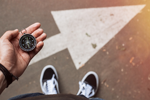 Hipster traveler holding navigational compass in the hand making choice in what direction to go