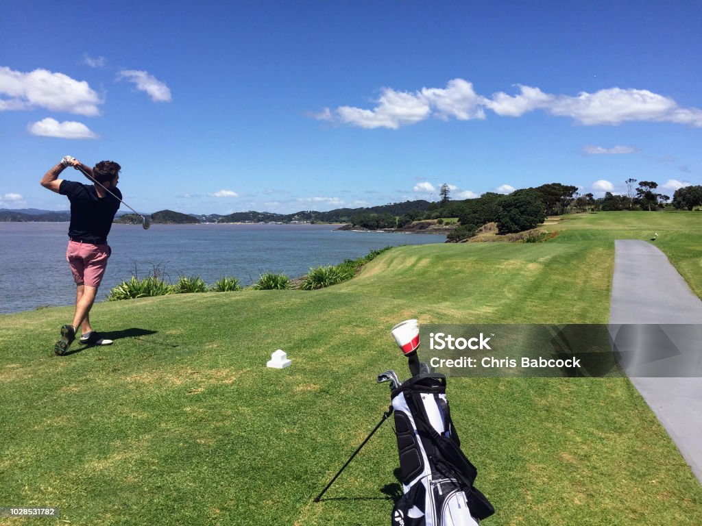 Man with a nice follow through playing golf along the coast of new zealand Golf Stock Photo