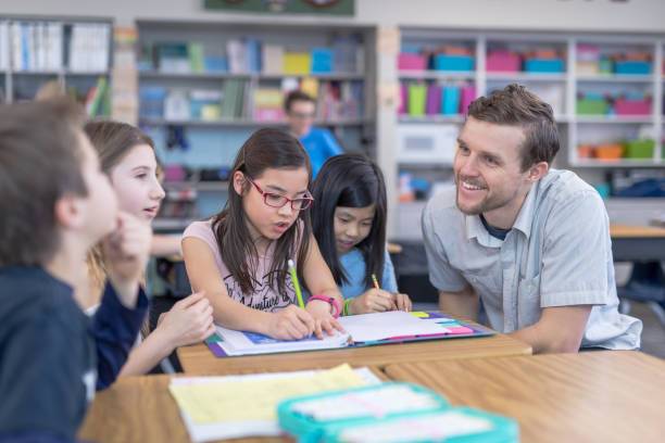 istock Male teacher helping several of his 4th grade students 1028549702