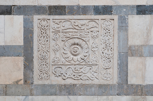 Bas-relief in white marble on the facade of the Carrara cathedral in Tuscany, Italy