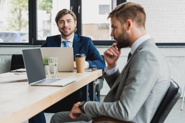 istock handsome young businessmen in suits using laptops and working together in office 1028602376