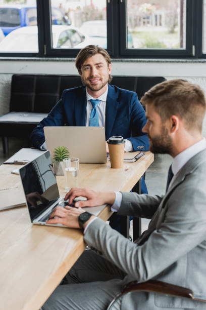 istock young businessmen in suits using laptops and working together in office 1028602386