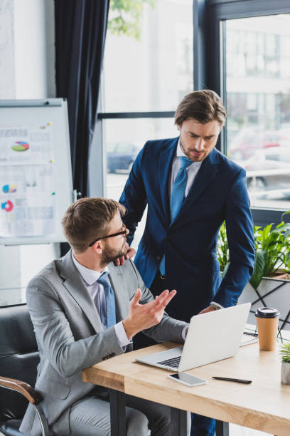 istock focused young businessmen discussing project and using laptop in office 1028602436