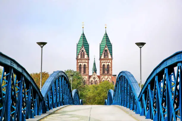 The Stuhlinger bridge leading to Herz-Jesu Cathedral, the gothic cathedral with a high tower in Freiburg, located in southern part of Black Forest of Germany.