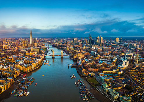 London, England - Panoramic aerial skyline view of London including Tower Bridge with red double-decker bus, Tower of London, skyscrapers of Bank District and other famous skyscrapers at golden hour