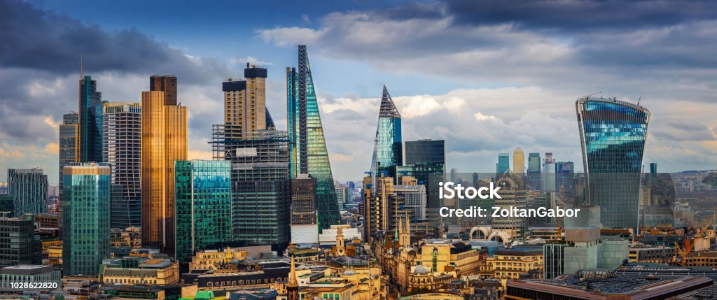 London, England - Panoramic skyline view of Bank and Canary Wharf, London's leading financial districts with famous skyscrapers London, England - Panoramic skyline view of Bank and Canary Wharf, London's leading financial districts with famous skyscrapers and other landmarks at golden hour sunset with blue sky and clouds London - England Stock Photo