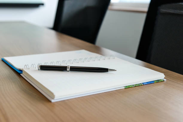 istock Pen on notepad for agenda kept on table in empty corporate conference room 1028623212