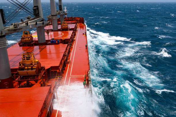 Cargo ship rolling in stormy Indian Ocean Cargo ship rolling in stormy sea. Huge waves under blue sky in Indian Ocean bulk carrier stock pictures, royalty-free photos & images