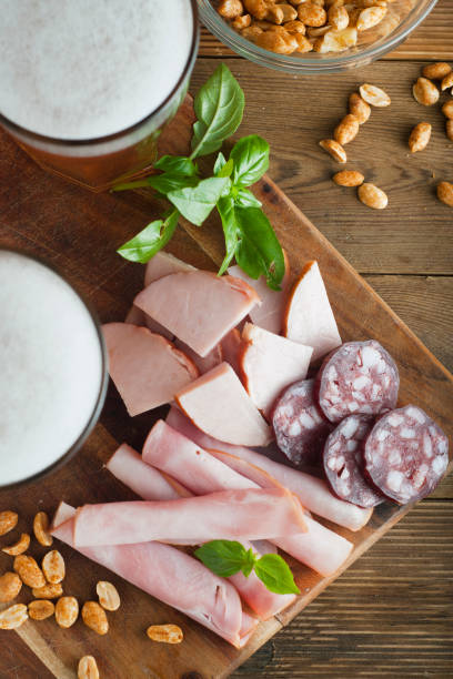 variety of meat snacks to beer: ham, rolled meat, with fresh basil and glass beer over dark wooden background. close up. - close to food and drink yummy food imagens e fotografias de stock