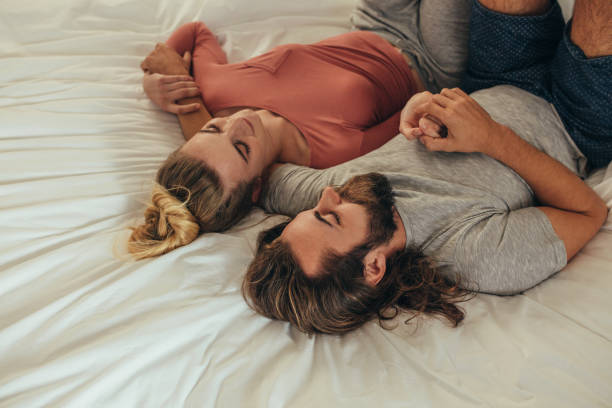istock Happy couple lying on bed together holding hands 1028679918