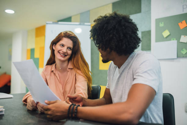 istock Businessman holding a document and looking at his redhead coworker 1028698482