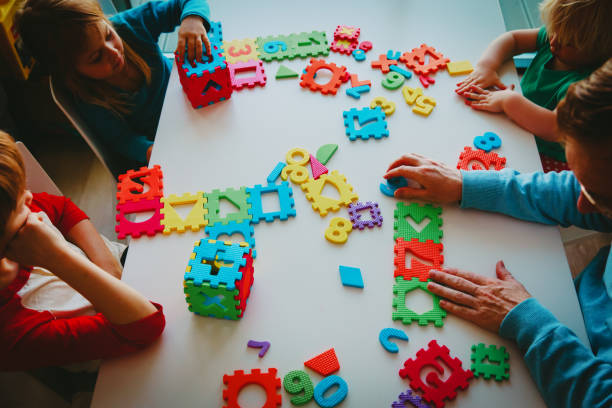 istock teacher and kids playing with number puzzle 1028702242