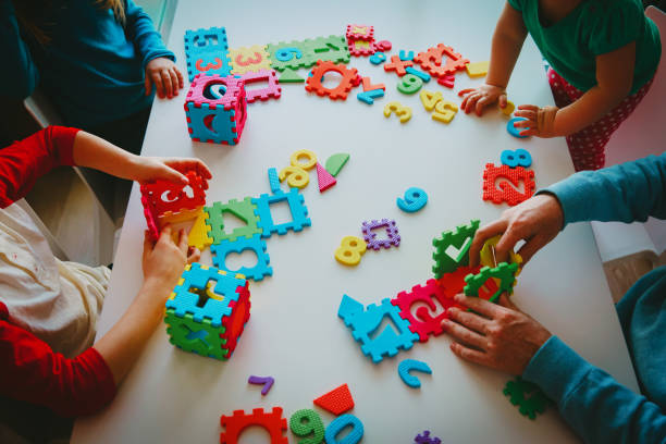 istock teacher and kids playing with number puzzle 1028702296
