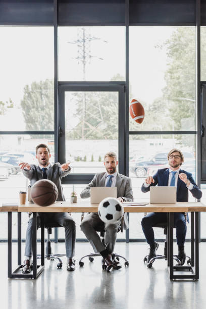istock young office workers in formal wear throwing balls while working with laptops in office 1028703740