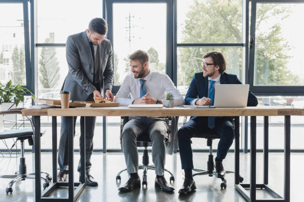 istock happy young office workers in formal wear eating pizza at workplace 1028703792