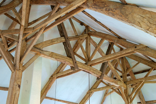 Looking up at the massive restored interior timber roof construction in a large  old French farmhouse