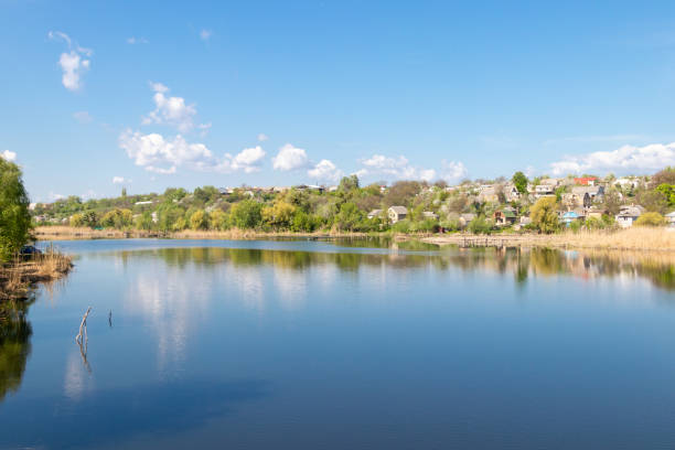 istock green coast of a beautiful small river with white clouds in reflection 1028710400