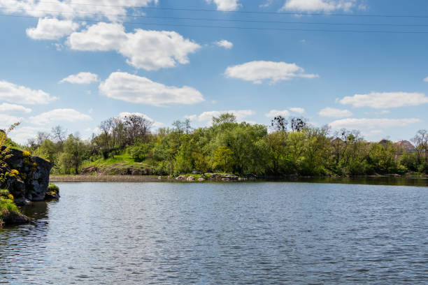 istock green coast of a beautiful small river with white clouds in reflection 1028710738