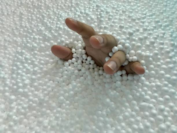 istock Hand rising from pile of white foam beads 1028716218