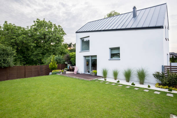 istock White house with windows and green garden with trees outside 1028745206