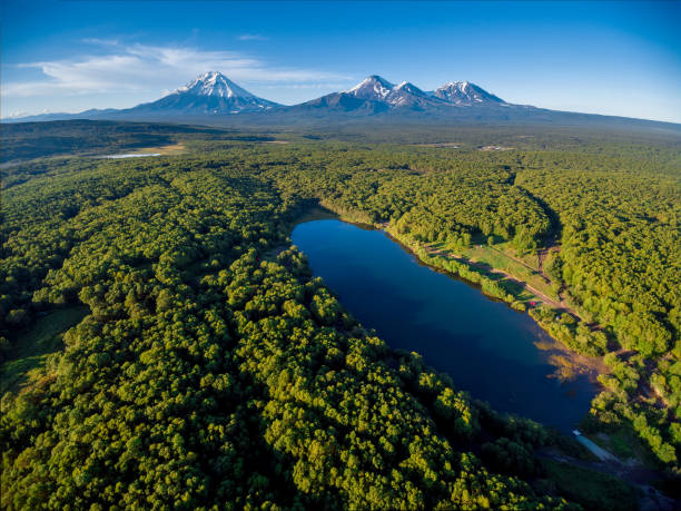 Lake in forest and volcano mountainscape at horizon aerial stock photo