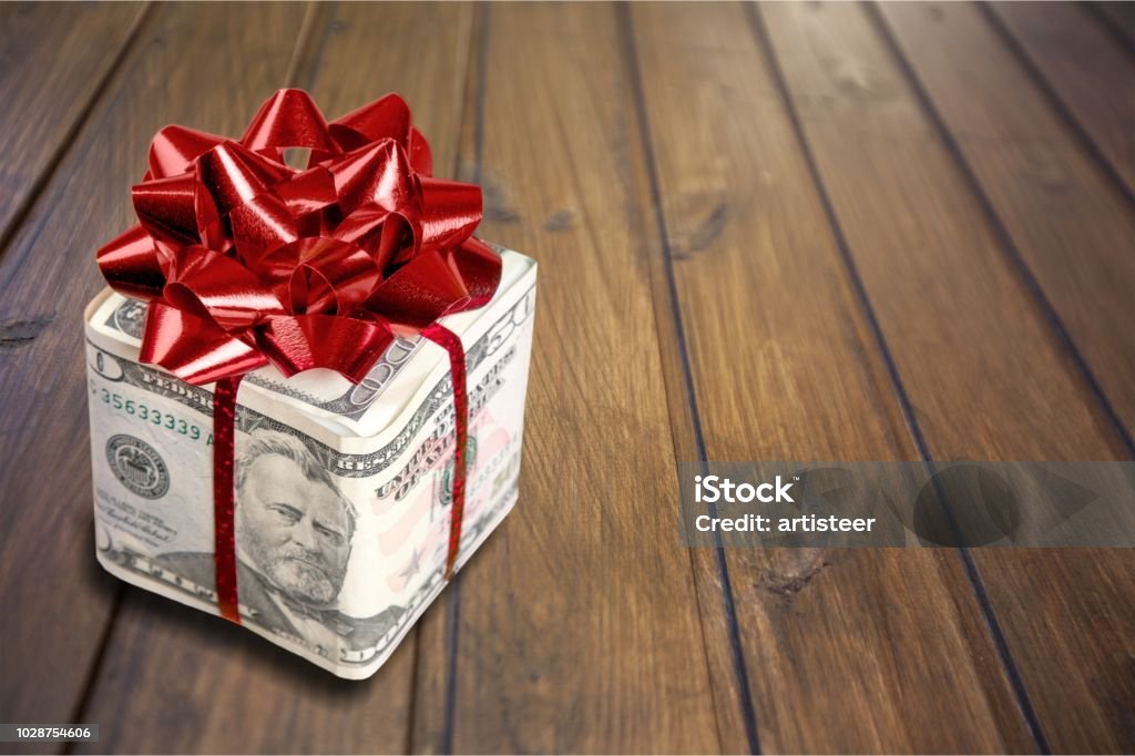 Gift. Christmas present with red bow wrapped in dollar banknotes isolated on white background Gift Stock Photo