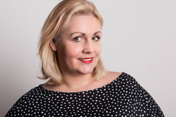 A happy attractive overweight woman in studio on a white background. A happy attractive overweight woman in studio standing against a white background. big fat lips stock pictures, royalty-free photos & images
