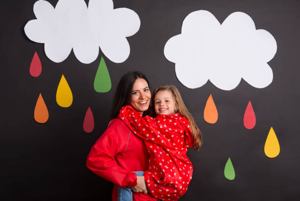 A small girl with her mother on a black background with clouds and raindrops.