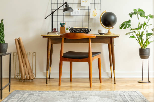 istock Plant next to chair and desk with lamp typewriter and globe in classic workspace interior. Real photo 1028760952